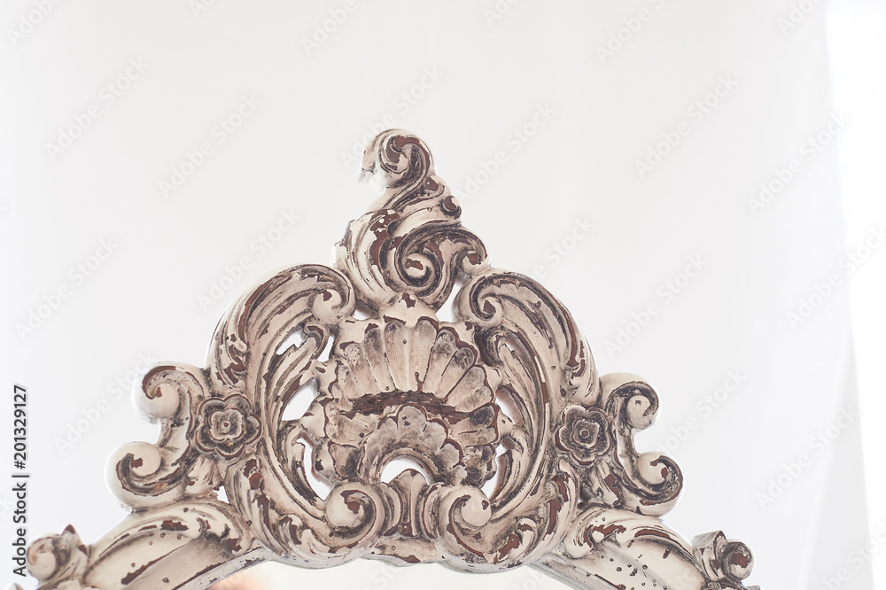 Element of old wooden carved frame on mirror.Bright interior. White frame with the effect of aging Element of old wooden carved frame on mirror.Bright interior. White frame with the effect of aging