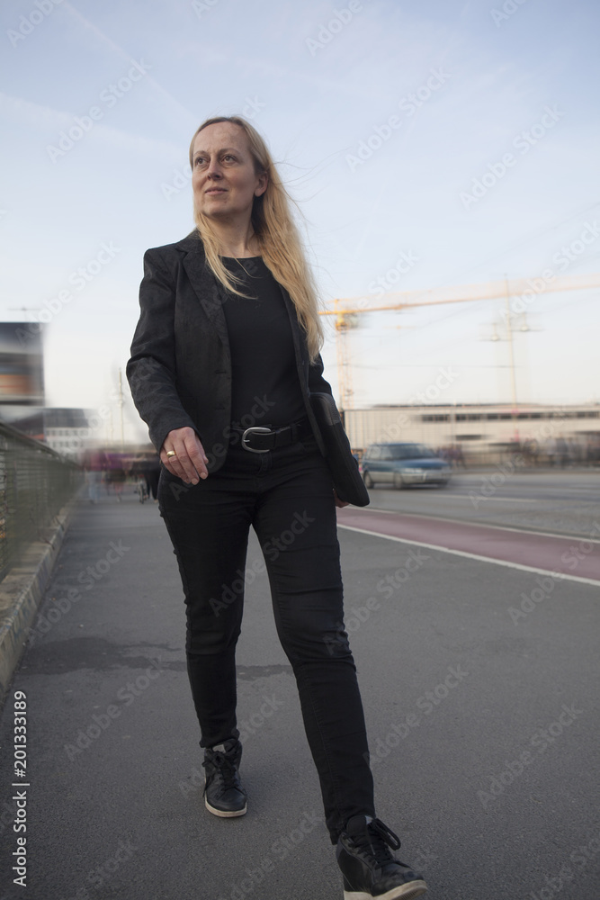 Mujer de negocios decidida andando por la calle con una carpeta. Mujer de negocios decidida andando por la calle con una carpeta.