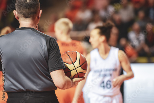 Referee holds the ball during women basketball match