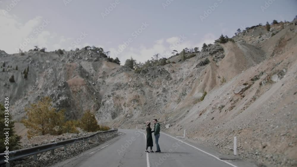 Stylish young couple walking on the mountain road Stylish young couple walking on the mountain road