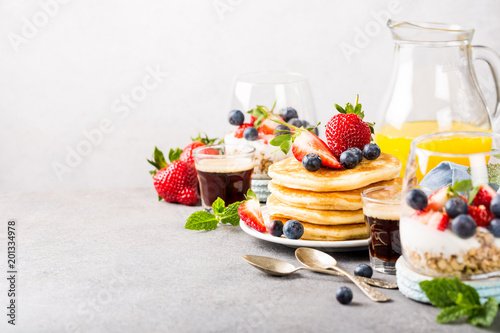 Breakfast background with fresh pancakes and berries on light gray concrete table. Healthy food concept with copy space.