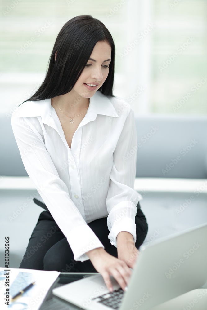 successful young woman sitting at a desk on a blurred background. successful young woman sitting at a desk on a blurred background.