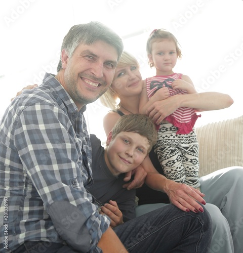 family with two children sitting together and looking at camera