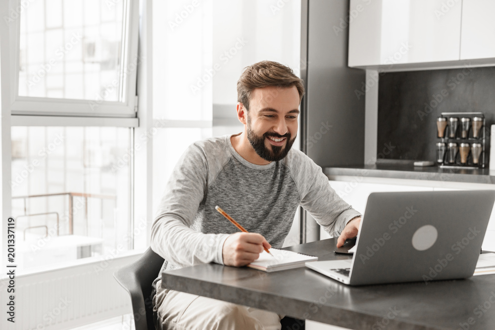 Fototapeta premium Portrait of a happy young man working on laptop