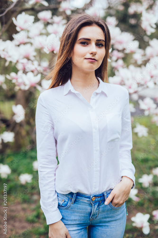 Outdoor portrait of a young beautiful woman near magnolia tree with flowers. Outdoor portrait of a young beautiful woman near magnolia tree with flowers.