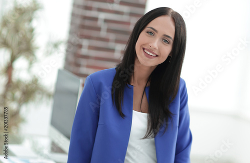 Free Download Attractive young businesswoman standing near desk in the office - GFXLoad