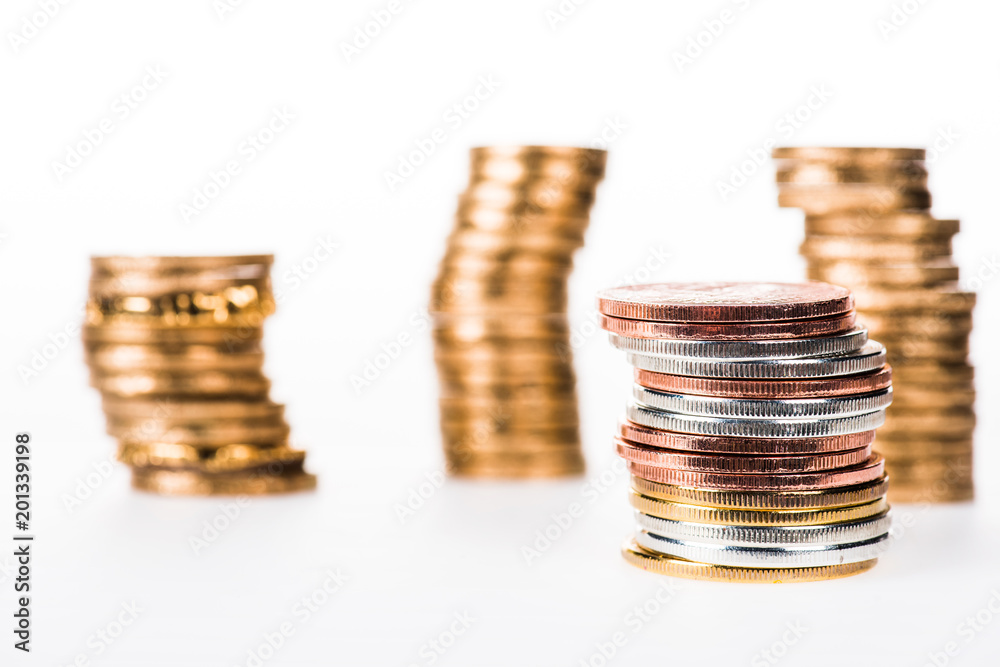 Selective focus of various stacked shiny coins isolated on white Selective focus of various stacked shiny coins isolated on white
