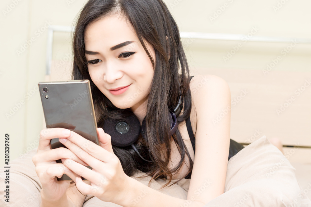 women sleep on bed in bedroom and holding smart phone women sleep on bed in bedroom and holding smart phone