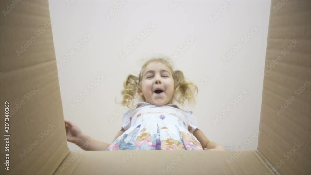 A little girl looks in the box, is surprised and happy to receive a surprise. The child opened a box with a gift.Slow Motion A little girl looks in the box, is surprised and happy to receive a surprise. The child opened a box with a gift.Slow Motion