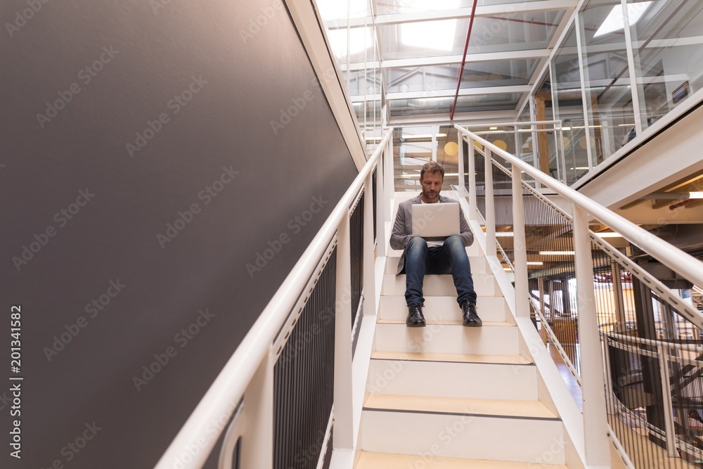 Businessman using laptop on staircase Businessman using laptop on staircase