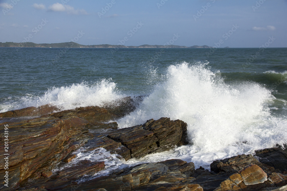 The waves breaking on a stony beach, forming a spray in Thailand The waves breaking on a stony beach, forming a spray in Thailand