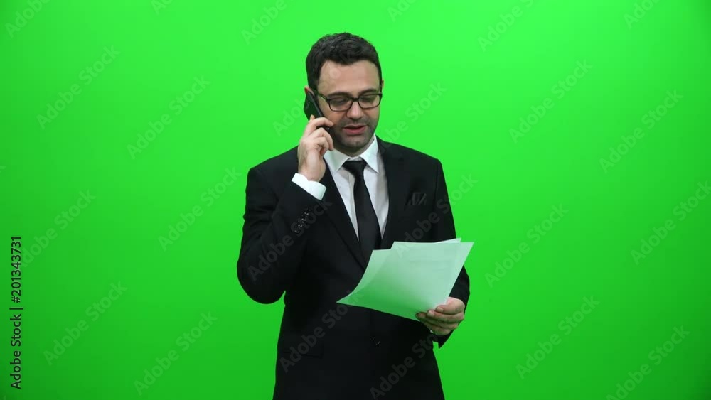 Businessman Talking On The Phone And Holding Papers On A Green Screen Businessman Talking On The Phone And Holding Papers On A Green Screen