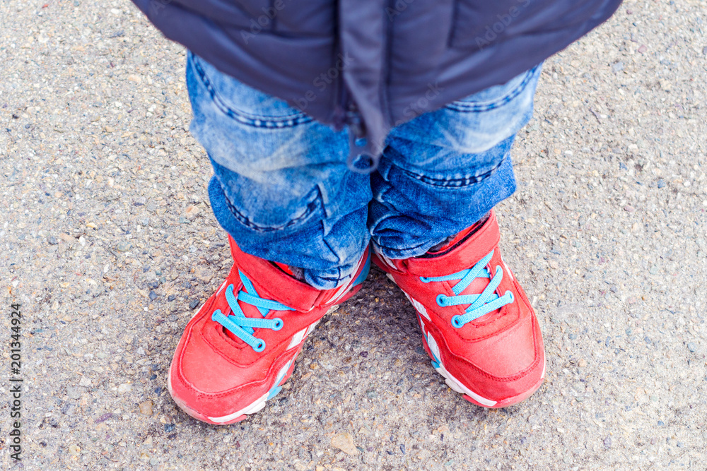children's legs in red sneakers and jeans