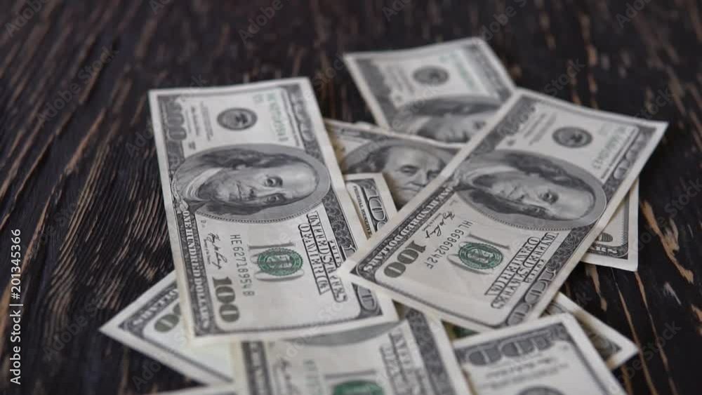 One hundred dollar bills falling on the table. One hundred dollar bills falling on the table.