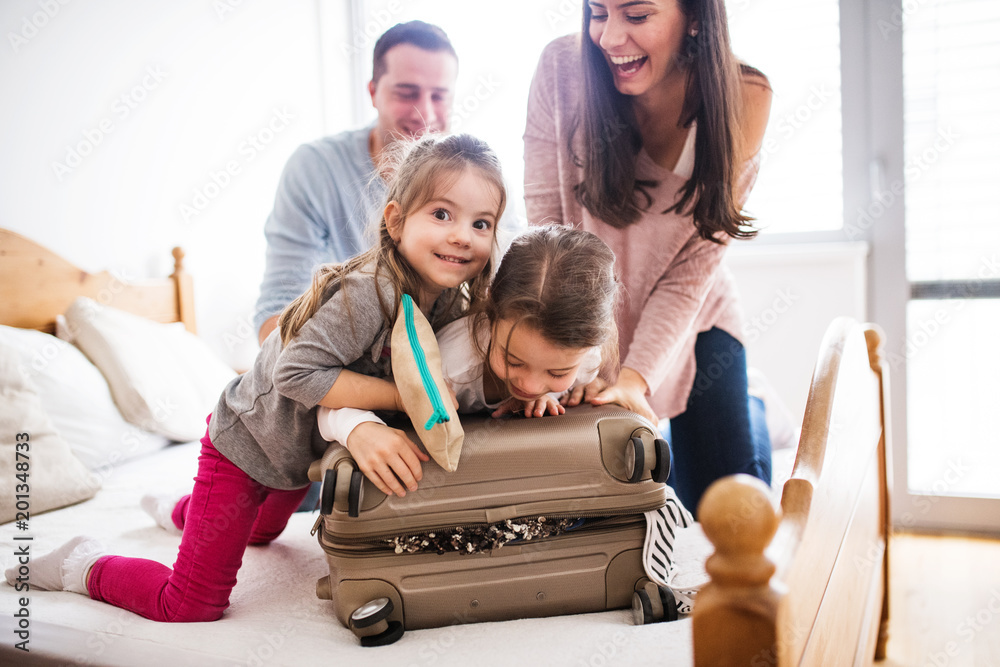 Young family with two children packing for holiday. - obrazy, fototapety, plakaty 