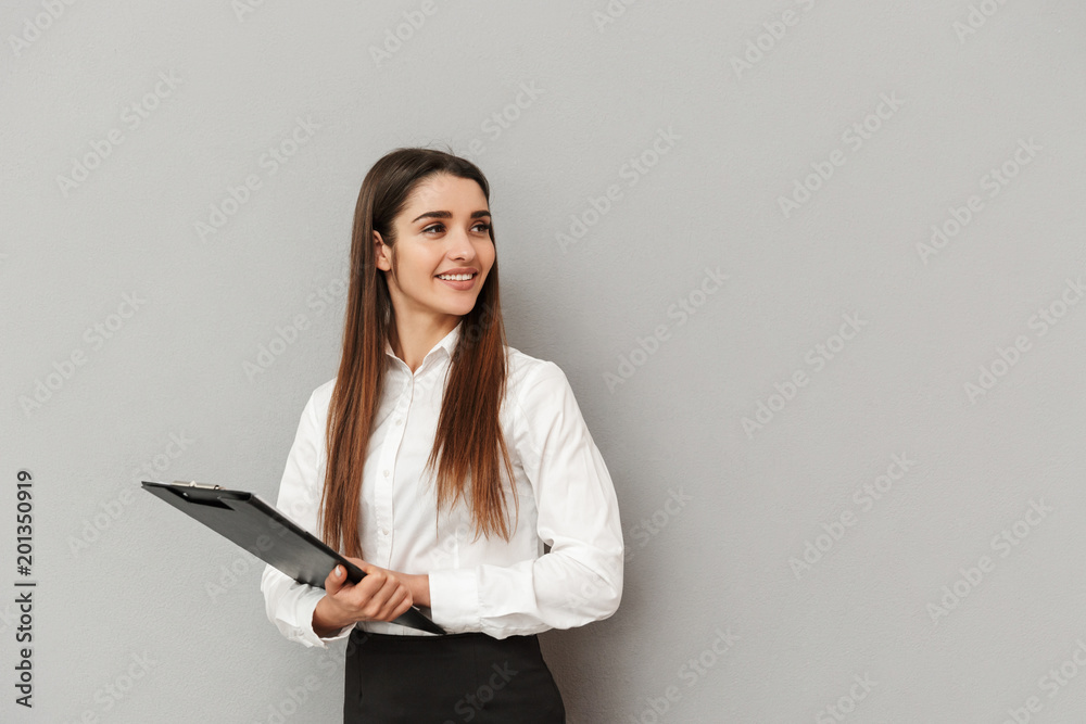 Photo of businesslike woman in white shirt and black skirt holding clipboard with documents in office and looking aside on copyspace, isolated over gray background Photo of businesslike woman in white shirt and black skirt holding clipboard with documents in office and looking aside on copyspace, isolated over gray background