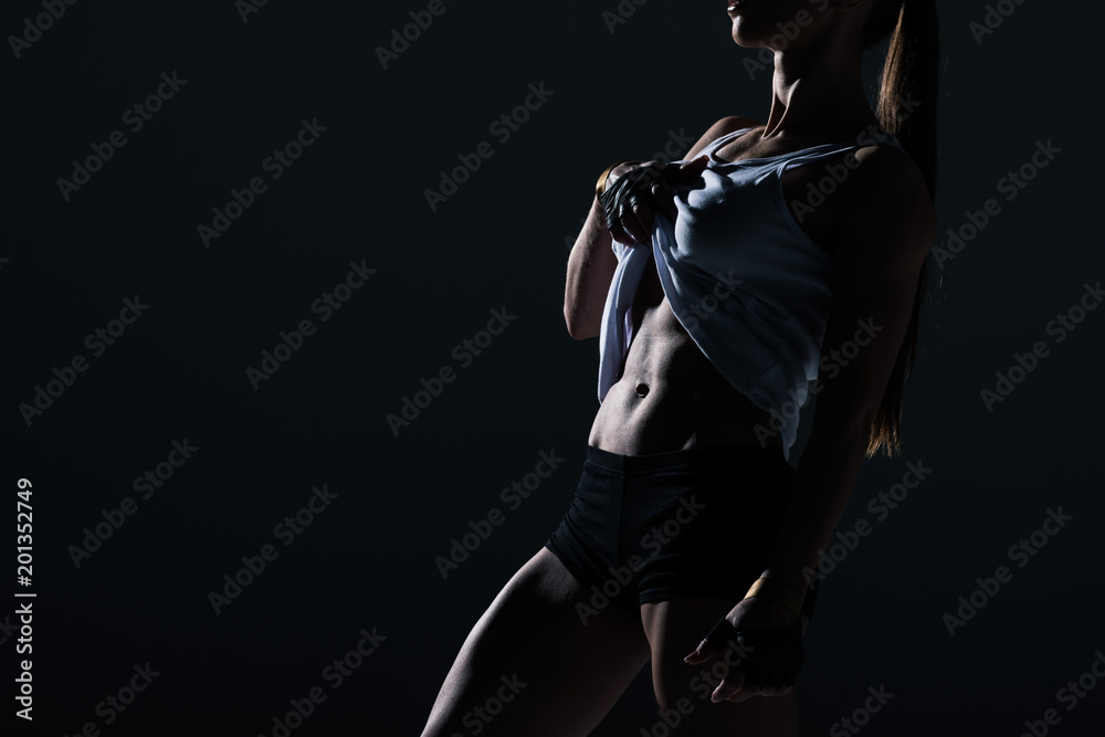 silhouette of muscular sportswoman showing abs, isolated on black