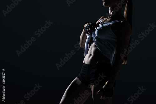 silhouette of muscular sportswoman showing abs, isolated on black