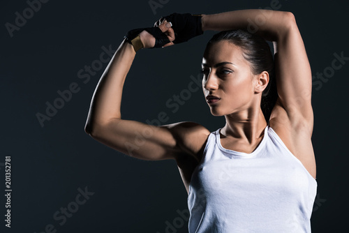 strong sportswoman showing muscular biceps, isolated on grey photo