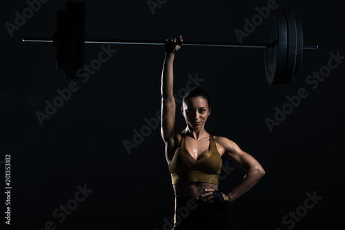 attractive strong bodybuilder holding barbell, isolated on black