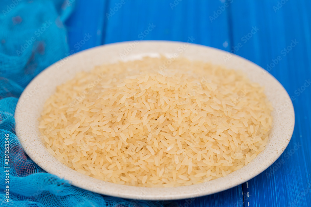 uncooked rice on plate on wooden background uncooked rice on plate on wooden background