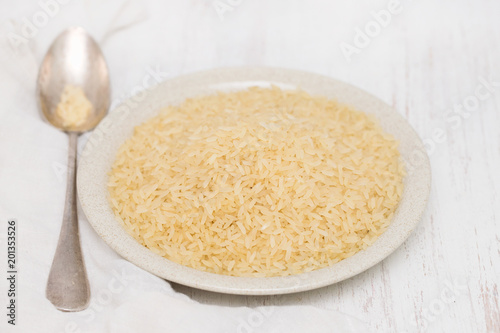 uncooked rice on plate on wooden background