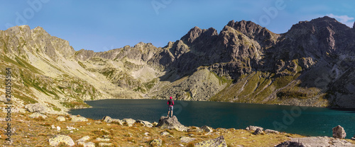 Górskie jezioro w Tatrach. Kobieta stojąca nad brzegiem jeziora. Turystyka górska.
