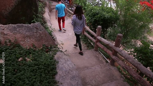 KHOANG NHA TRANG/VIETNAM - JUNE 20 2015: Vietnamese guy and long-haired brunette girl go down stony stairs in park at background of sea on June 20 in Khoang Nha Trang photo