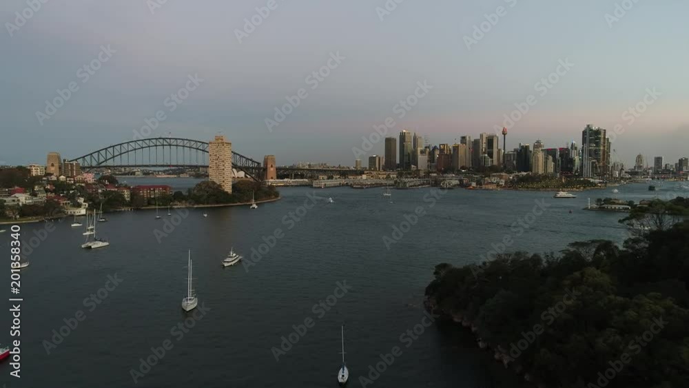 Balls Head reserve gum trees underneath flying camera towards Sydney city CBD landmarks at sunset.
Balls Head reserve gum trees underneath flying camera towards Sydney city CBD landmarks at sunset.