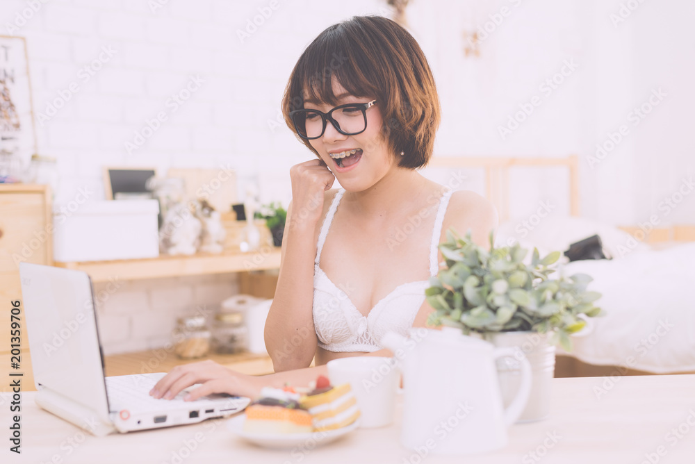 portrait of a young sexy beautiful and happy woman in bikini using laptop and lying