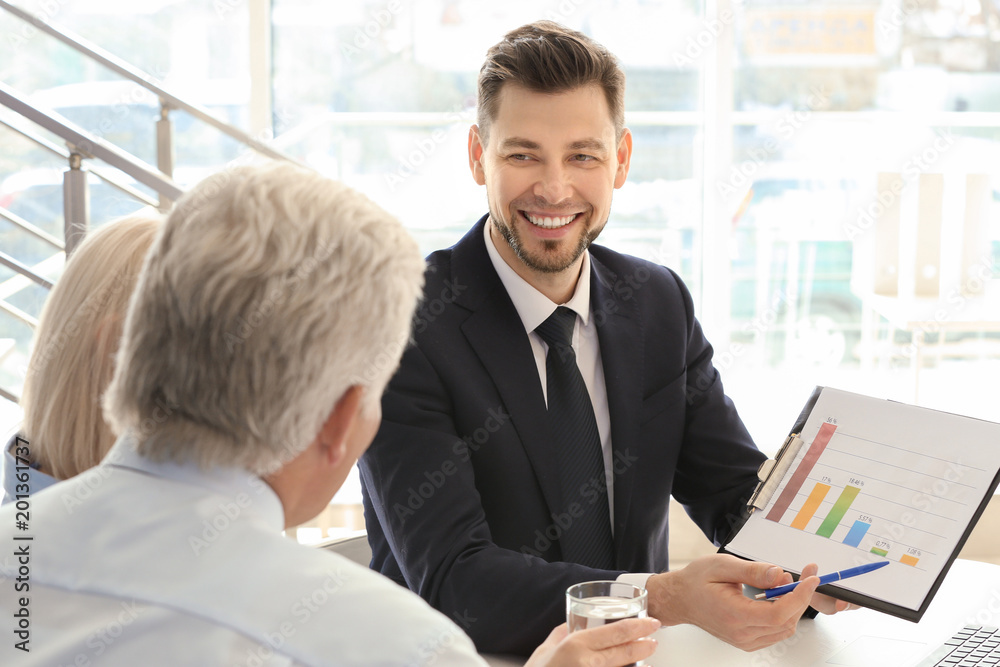 Male manager consulting mature couple in office Male manager consulting mature couple in office