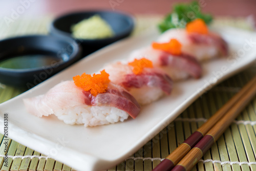 Hamachi sushi on white plate along with Japanese sauce and green leaf decoration, Japanese food, close up at sushi .. photo