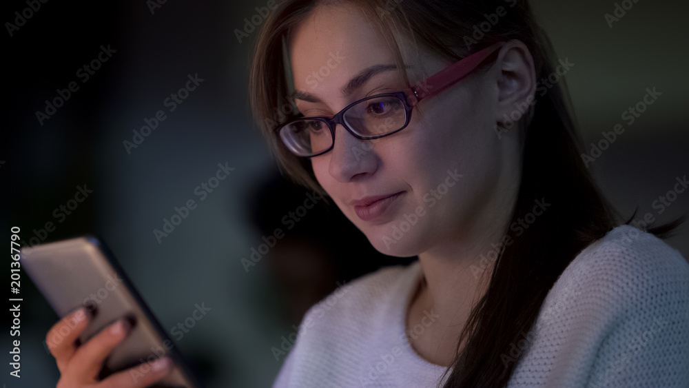 Young student reading text and smiling, launching new app on her modern gadget Young student reading text and smiling, launching new app on her modern gadget