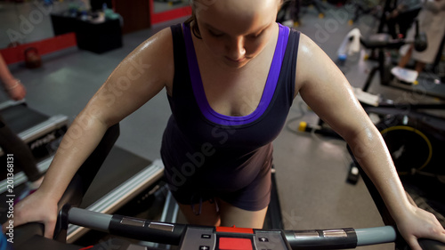 Persistent girl working hard on treadmill looking at monitor checking indicators