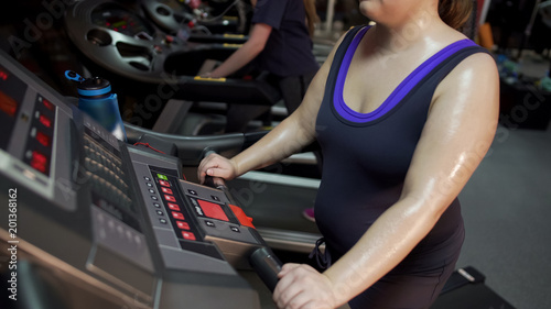 Sweaty overweight woman running on treadmill, weight loss exercises and diet