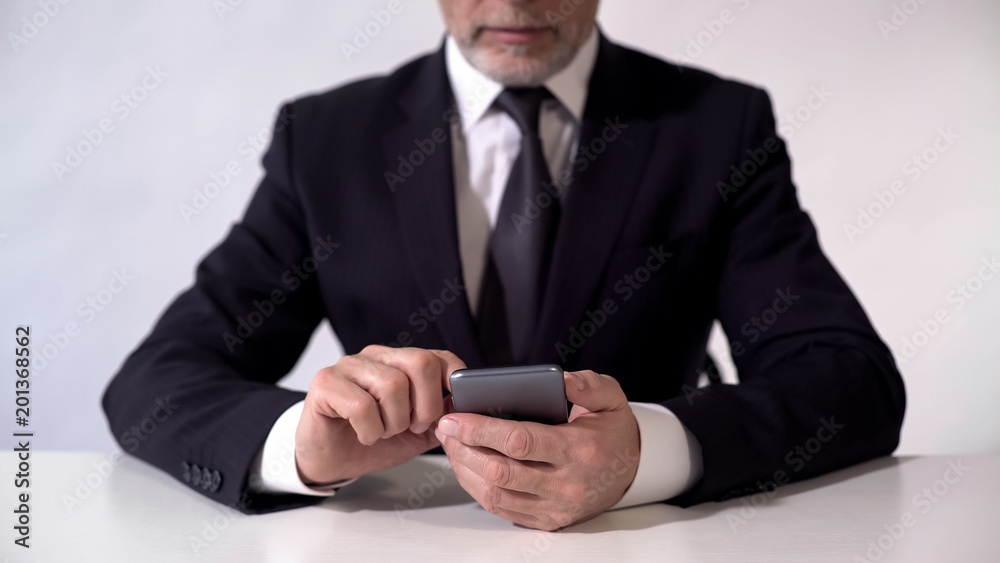 Middle aged businessman using smartphone, checking news about stock exchange Middle aged businessman using smartphone, checking news about stock exchange