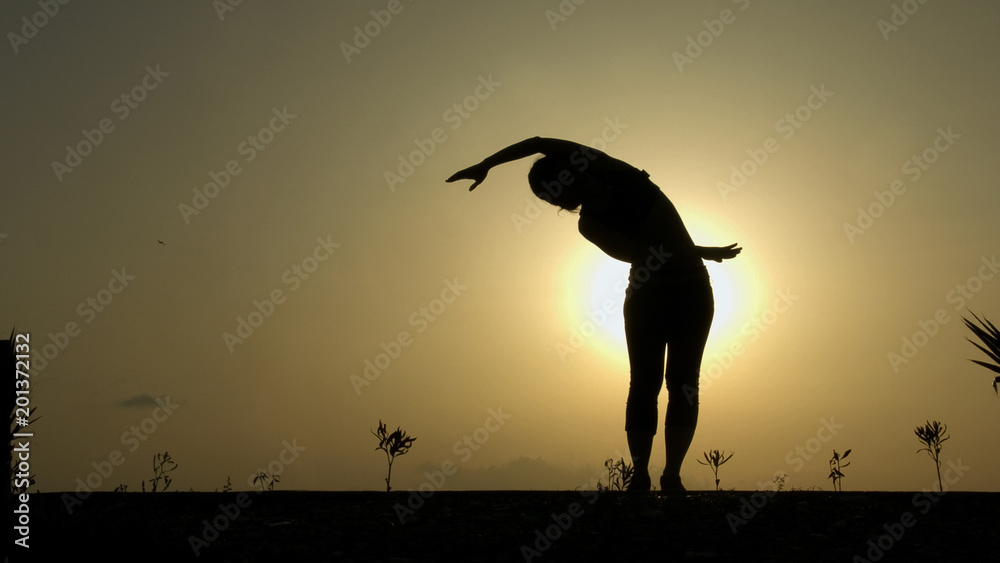 Bend yoga pose, silhouette of woman exercising and meditating against sunset