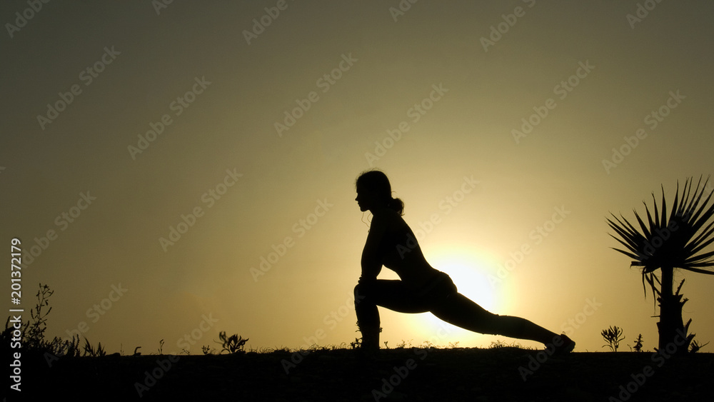 Female silhouette practicing yoga against sunset sky, inner harmony, tranquility
