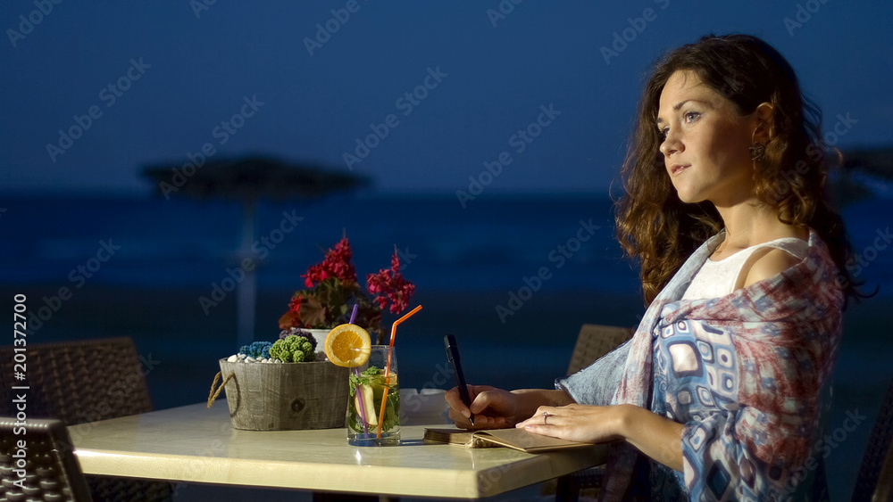 Obraz premium Romantic female writer thinking her new book, relax at seaside restaurant