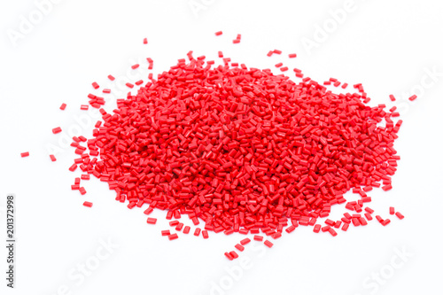 Red plastic polymer granules on white background.