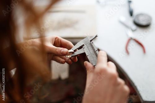 Making of jewelry. Jeweller measures the wedding ring using calipers. © Seweryn