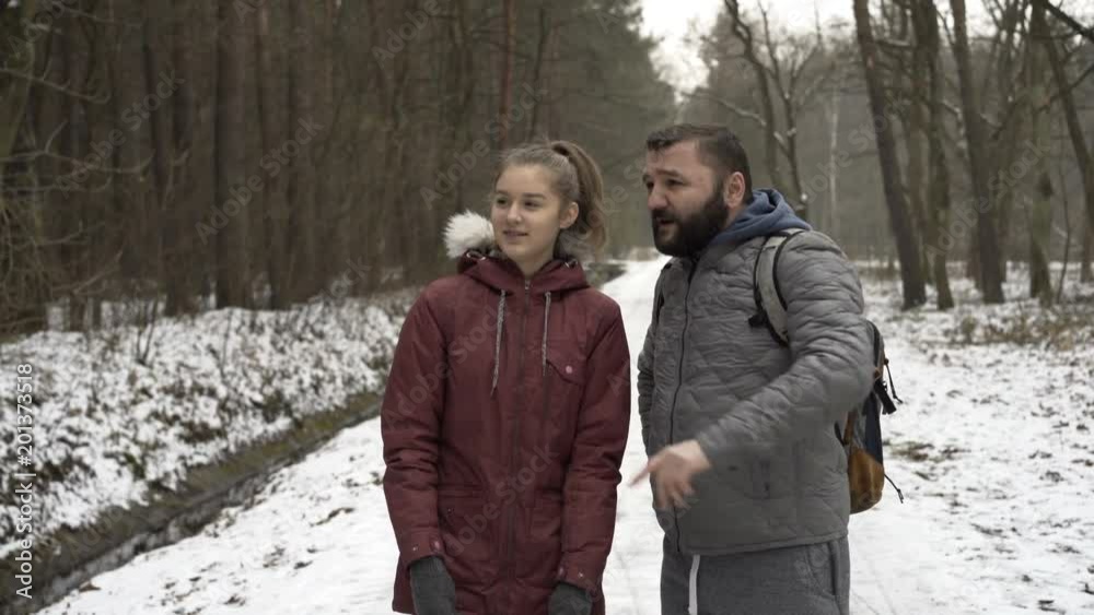 Father talking with daughter during trekking in winter forest
