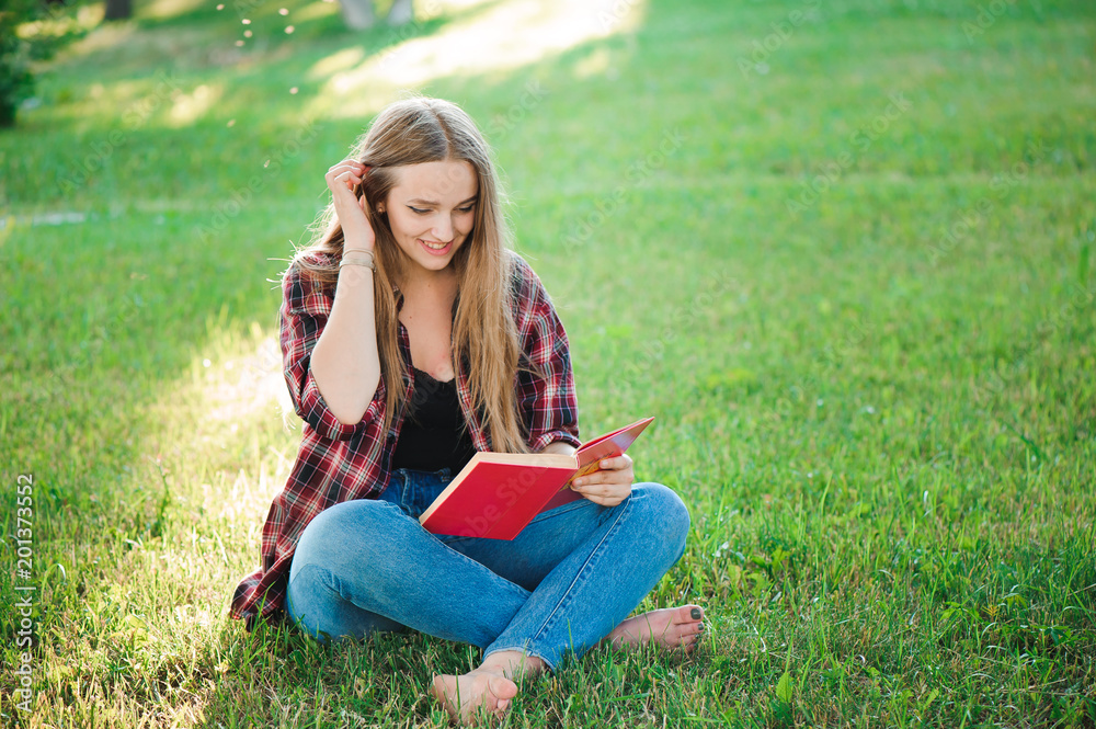 pretty blond young woman reading a book at park