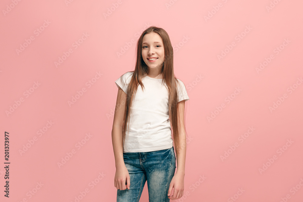 The happy teen girl standing and smiling against pink background. The happy teen girl standing and smiling against pink background.