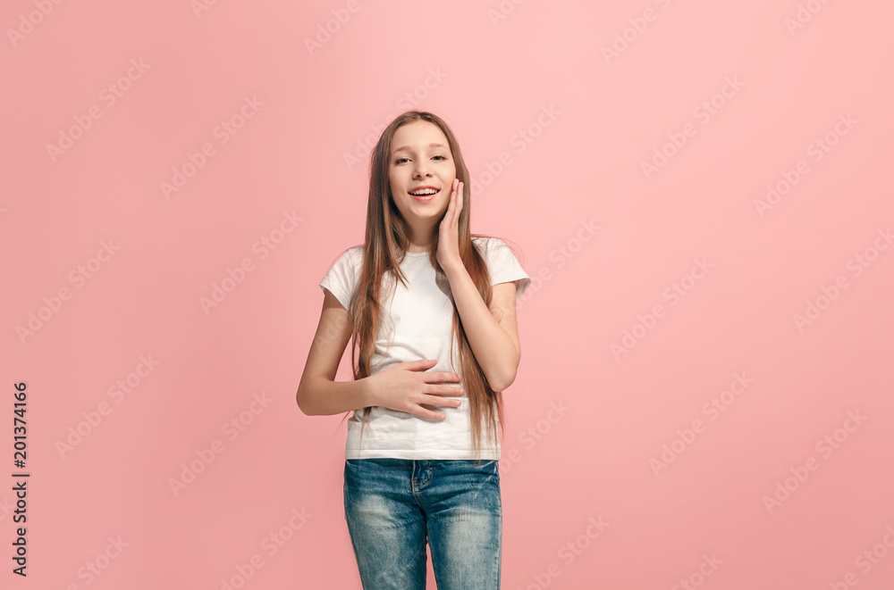 The happy teen girl standing and smiling against pink background. The happy teen girl standing and smiling against pink background.