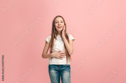 The happy teen girl standing and smiling against pink background.