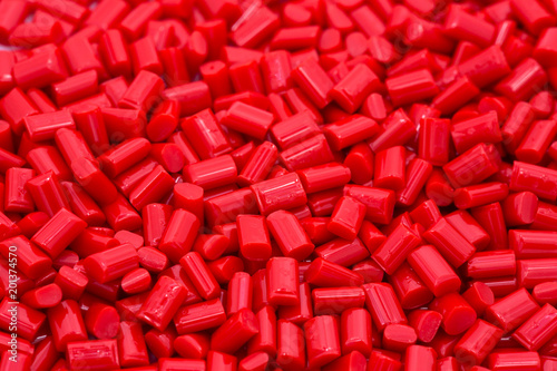 Red plastic polymer granules on white background.
