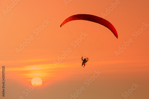 Silhouette of paraglider flying in the evening sky with sunset.