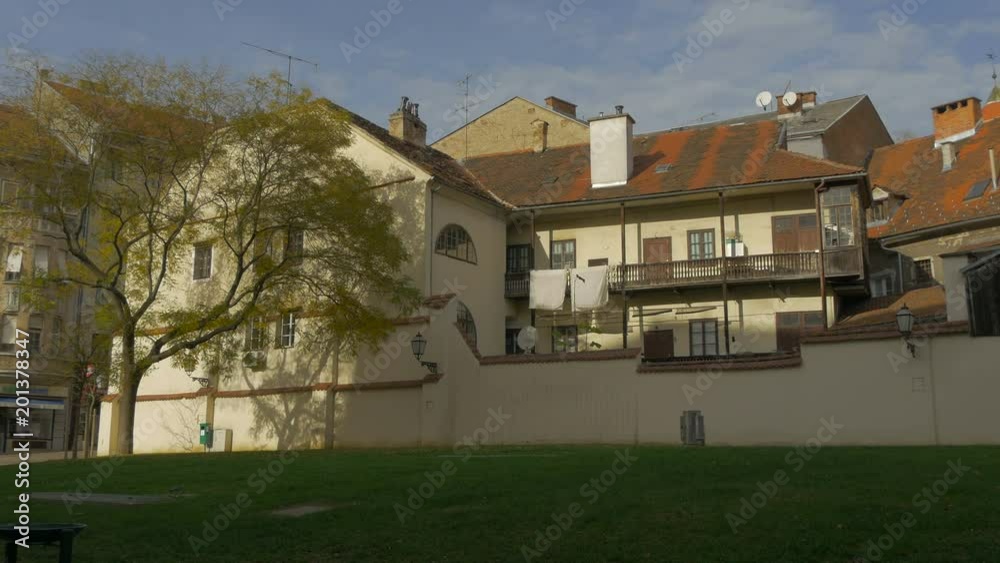 A tree by a house with wooden elements A tree by a house with wooden elements
