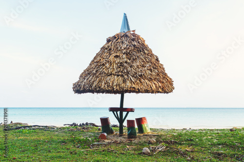 Thatched umbrella shading a picnic table on a sandy beach photo